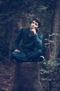 Man sitting on a tree stump looking deep in thought